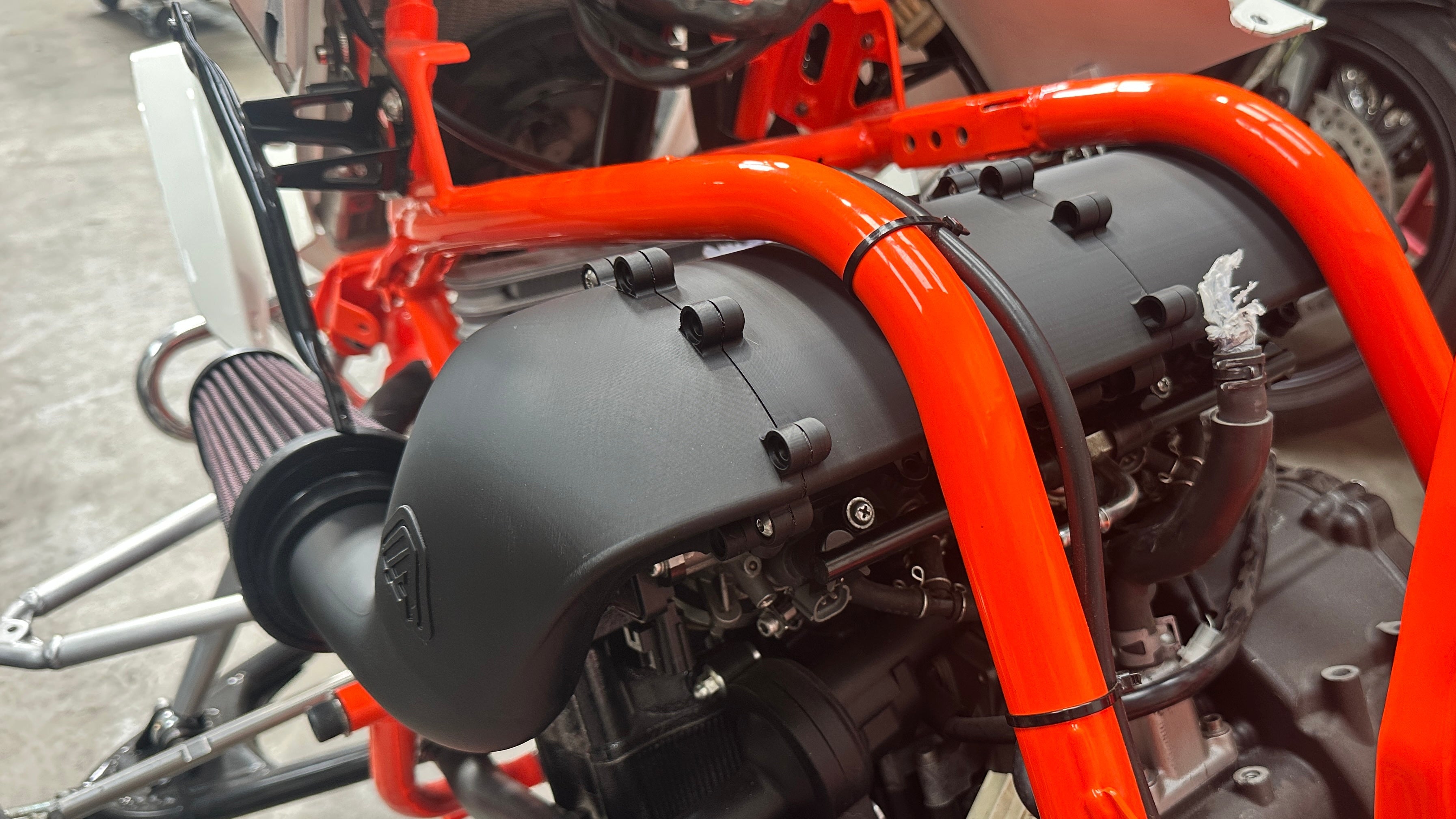 Close-up of a motorcycle engine with orange frame and black components.